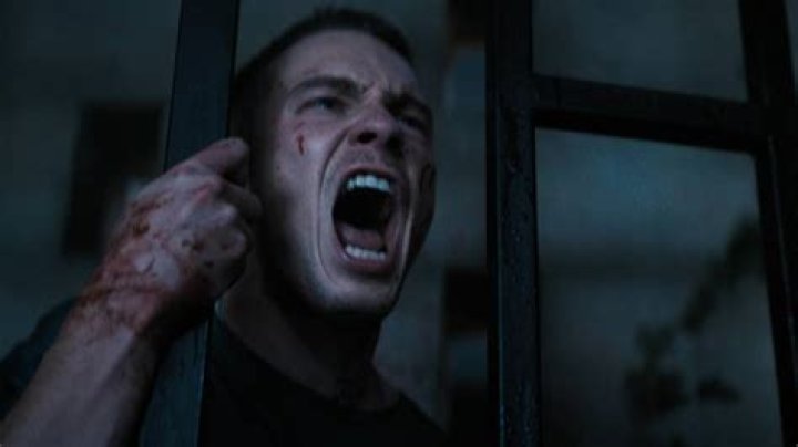 Drew Starkey screams while holding onto a vertical bar with a bloody hand in Hellraiser.