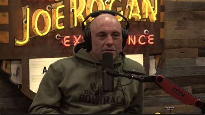 Joe Rogan talking into microphone wearing white shirt